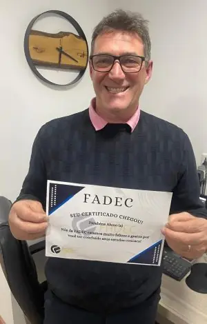 Aluno da FADEC sorrindo com o cartão de conclusão